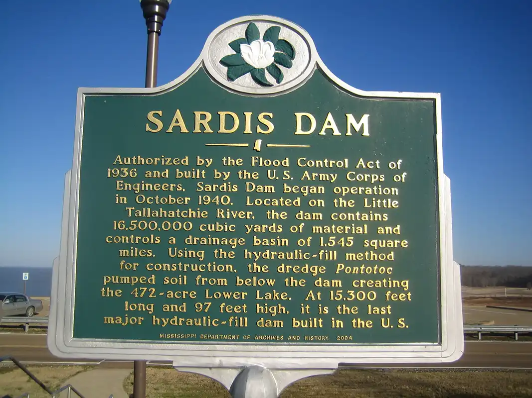 The Sardis Dam marker is at the end of the spillway (Spillway Road) at the Arty R. Tapp Overlook on Scenic Highway 315.